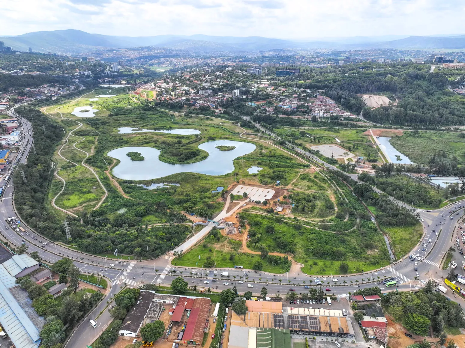Vue aérienne de lacs et d'espaces verts aménagés en ville, avec des collines à l'horizon